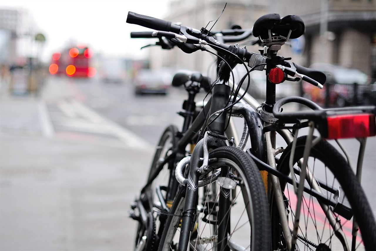 Two Bicycles Padlocked to a Metal Post on a City Street