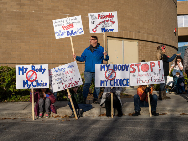 A small crowd outside the Loussac Library protested a mask mandate that the Anchorage Assembly is considering.