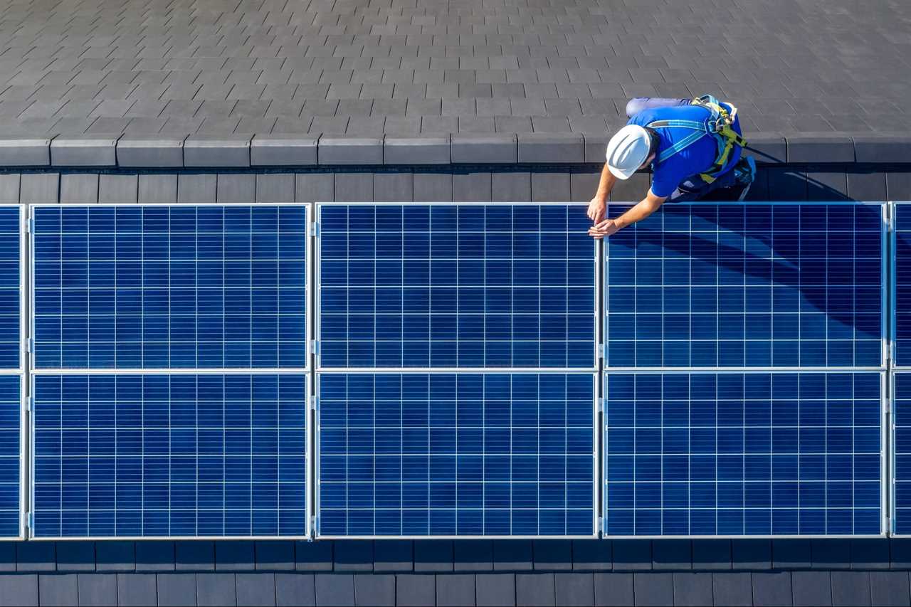 Solar panel installer installing solar panels on roof of modern house