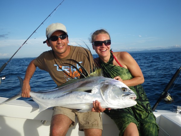 A man and a woman holding a fish after  fishing it in the deep sea