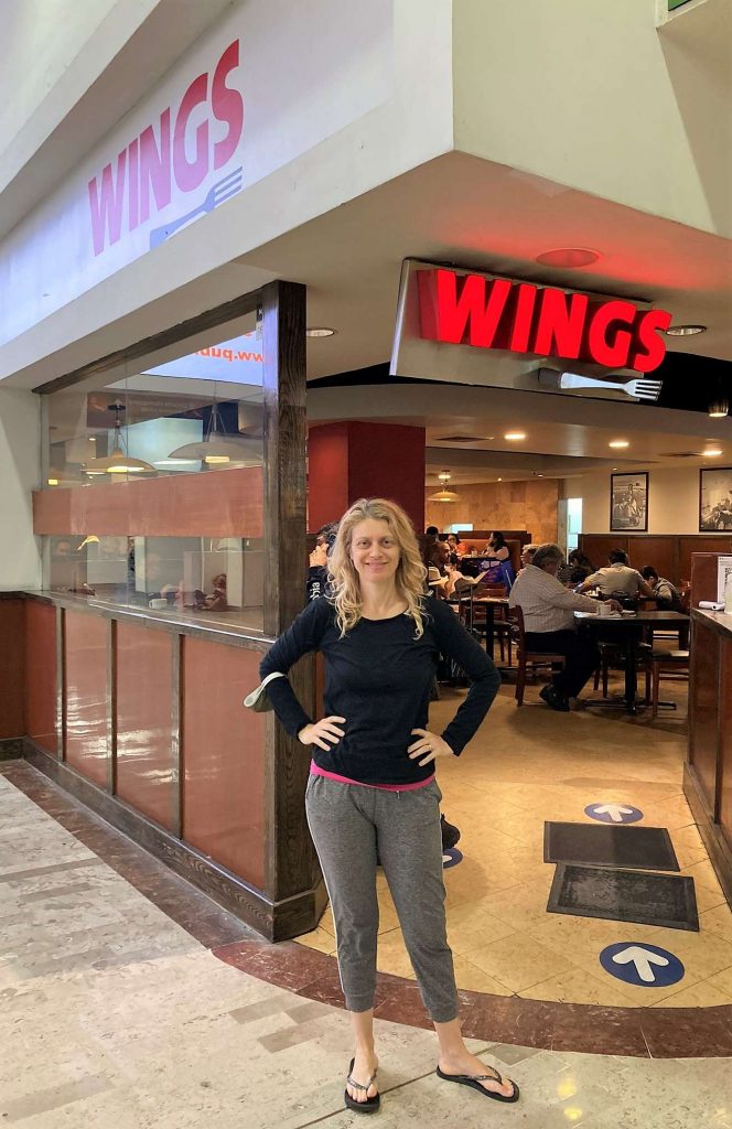 woman standing in front of wings restaurant at the mexico city airport