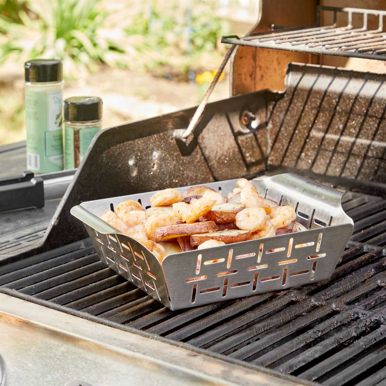 weber grill basket with shrimp and potatoes on a grill