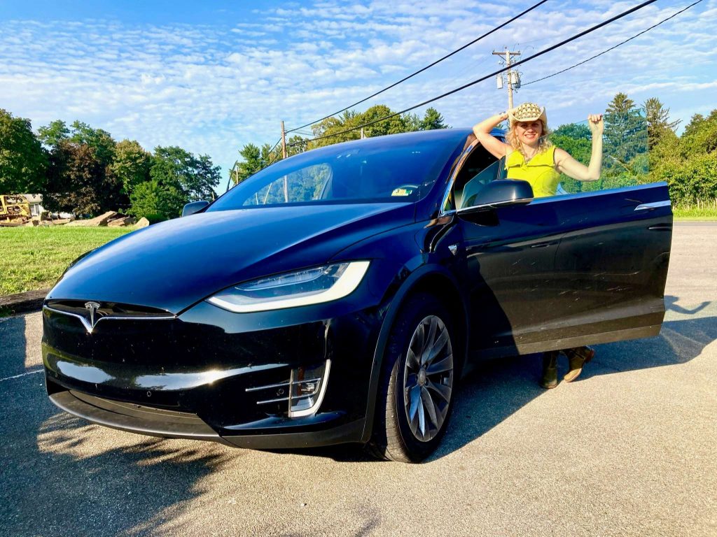 Woman standing behind the open door of tesla model x