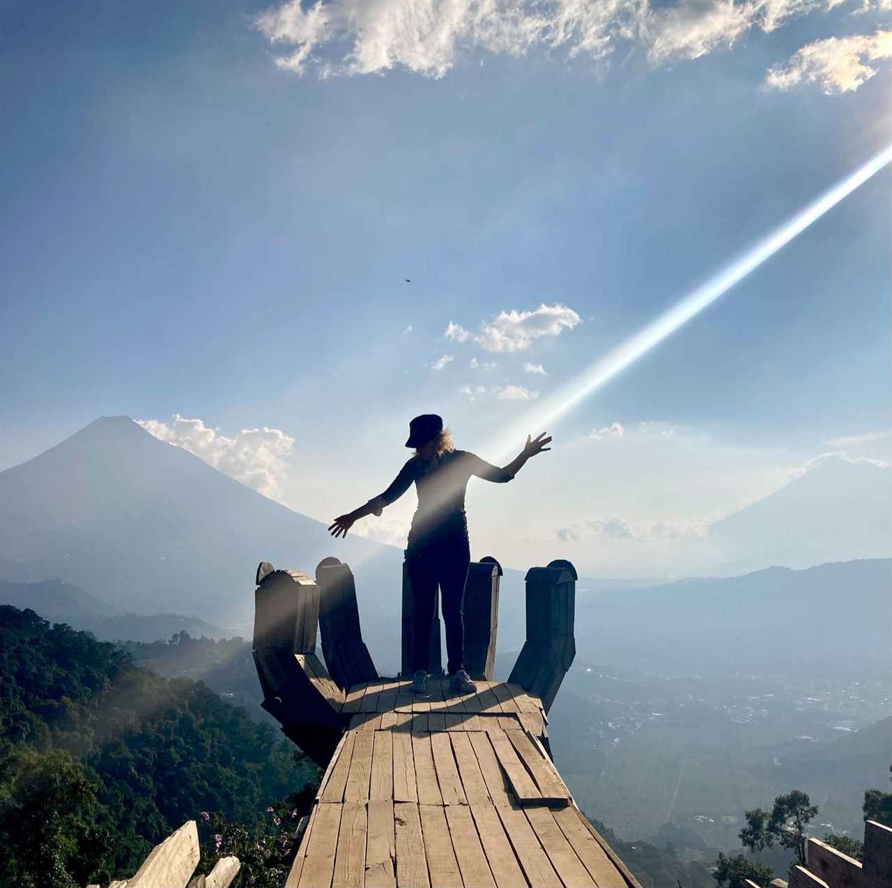 woman standing on a wooden hand on top of a mountain in altamira restaurant antigua