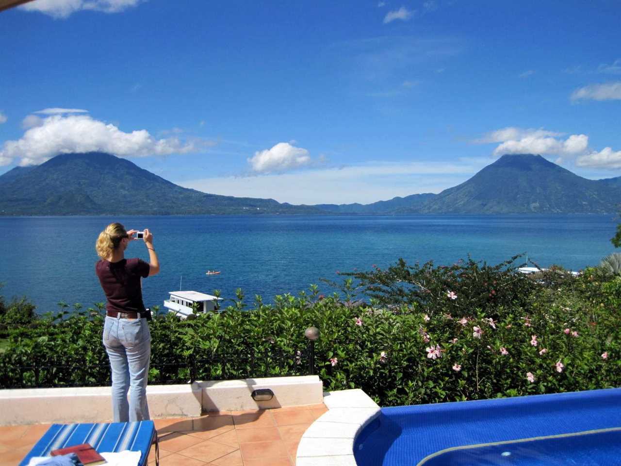 Woman near a pool taking a photo of Lake Atitlan in Panajachel