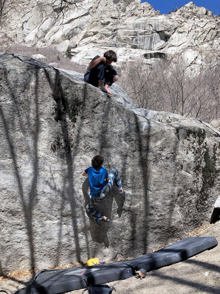 kid on top of a rock and another doing bouldering at little cottonwood canyon