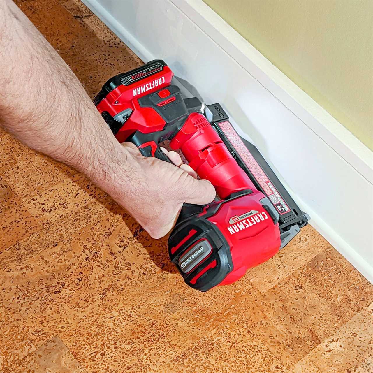 hand using a Craftsman Cordless 23 Gauge Nailer on the baseboards in a house