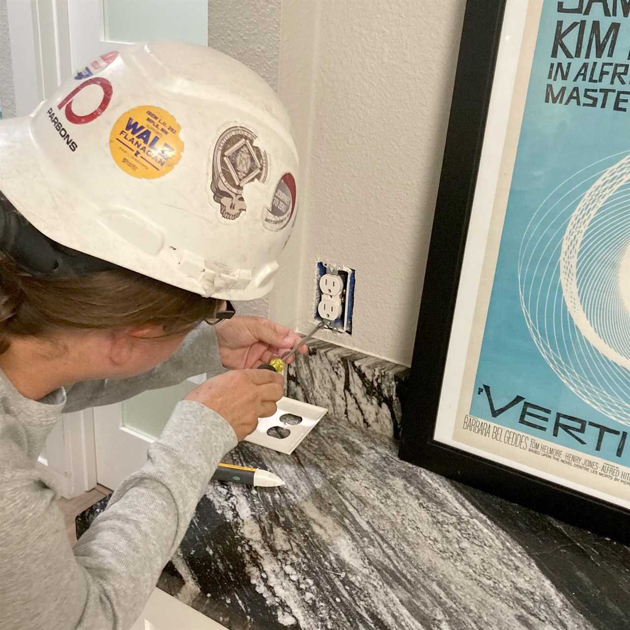 Ally Childress working on an electrical outlet in a hard hat