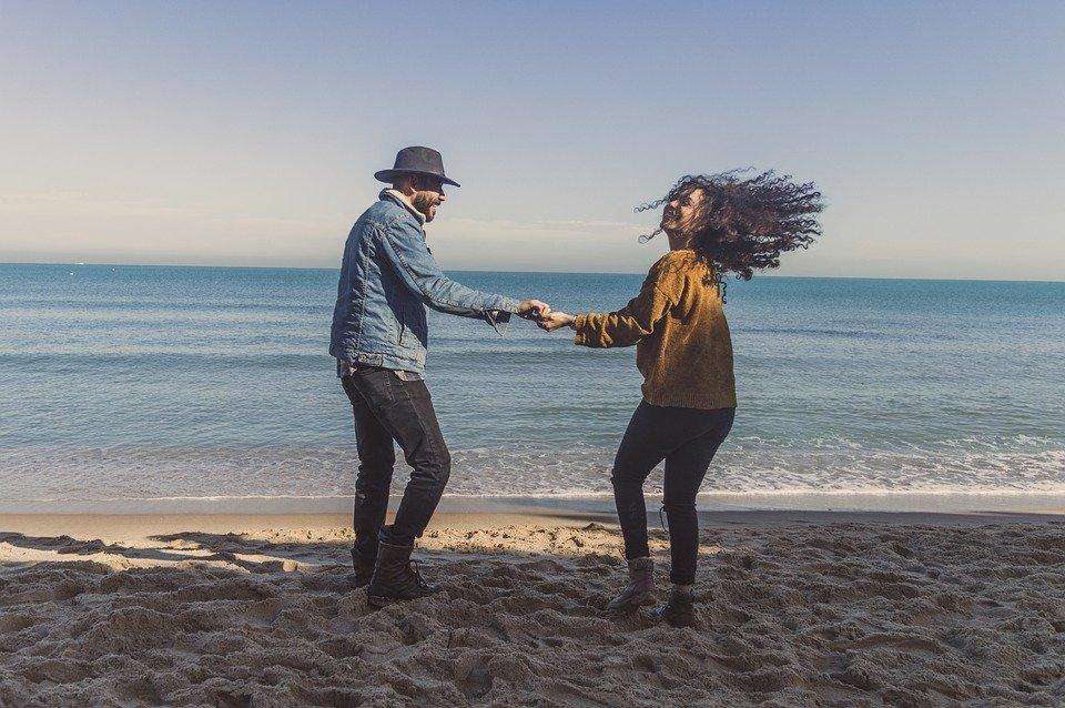 couple having fun on the beach shile holding both hands