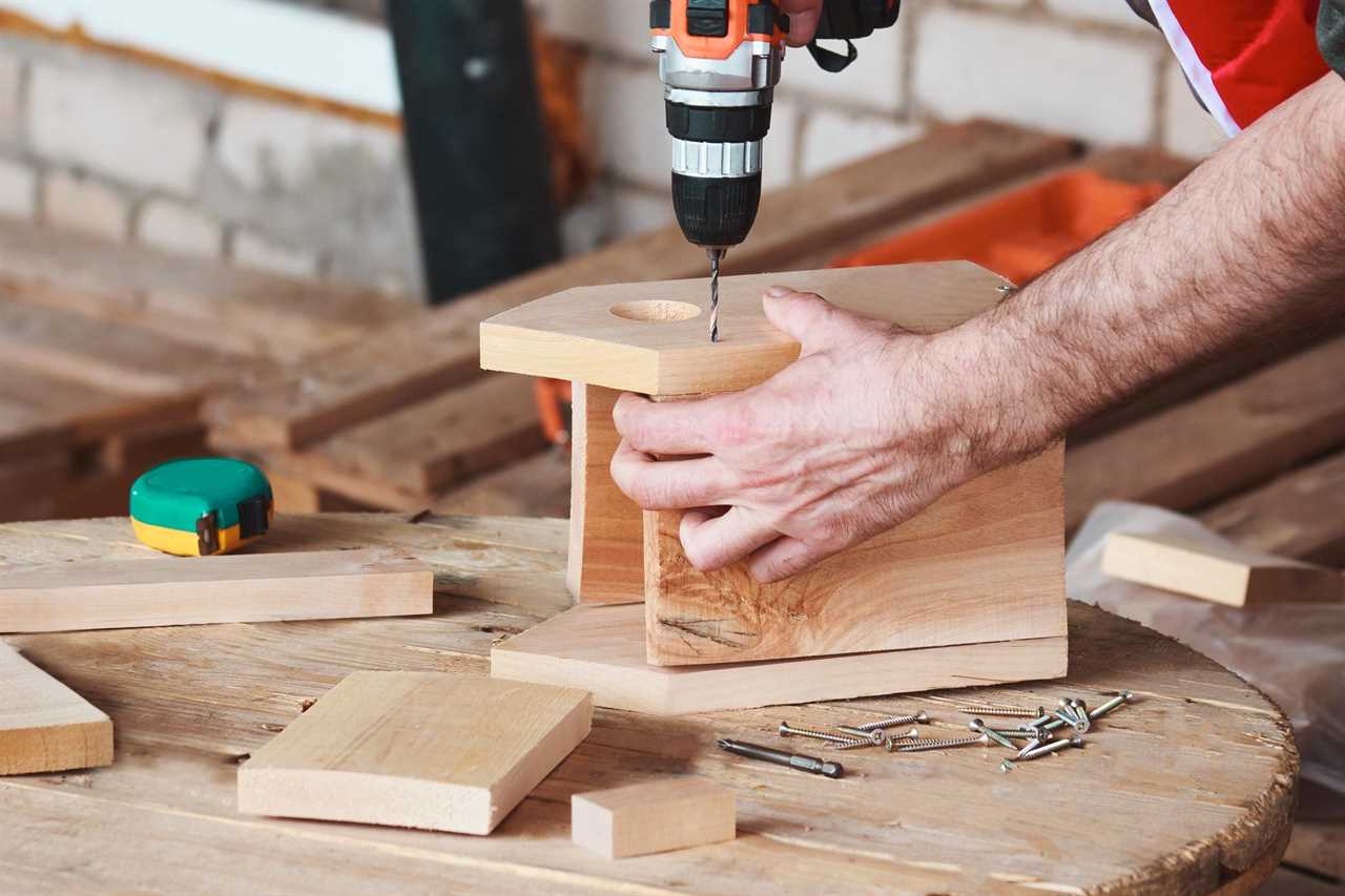 man builds a bird house and is attaching the front to the sides with a drill