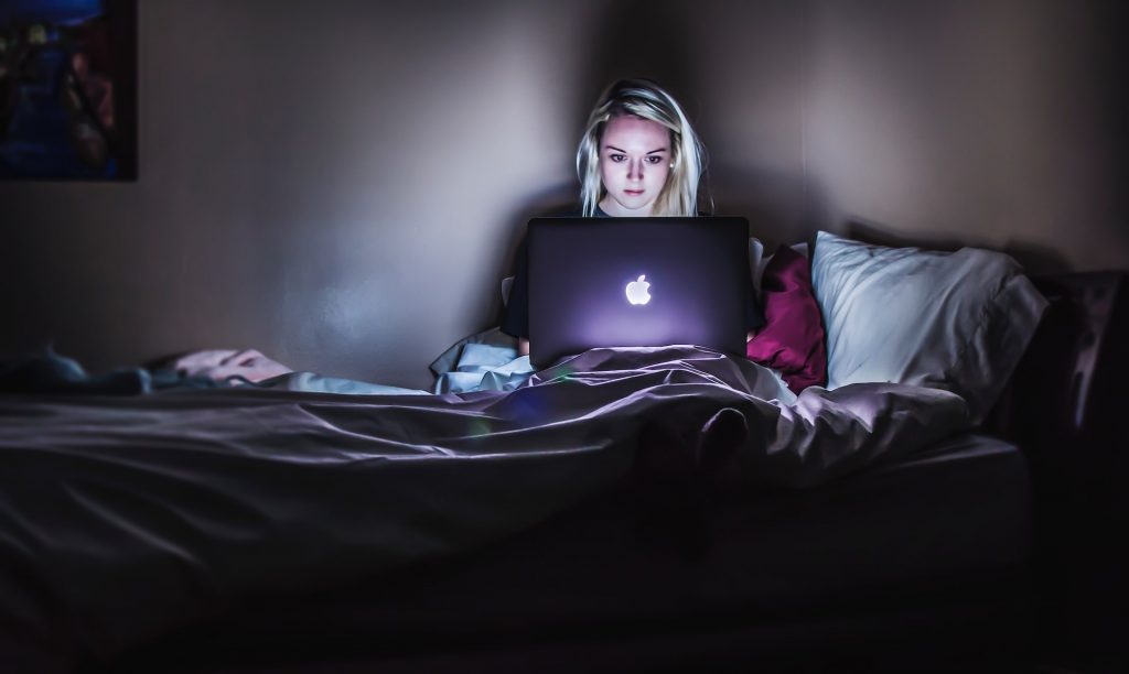 Woman in a dark room using a laptop for online psychotherapy