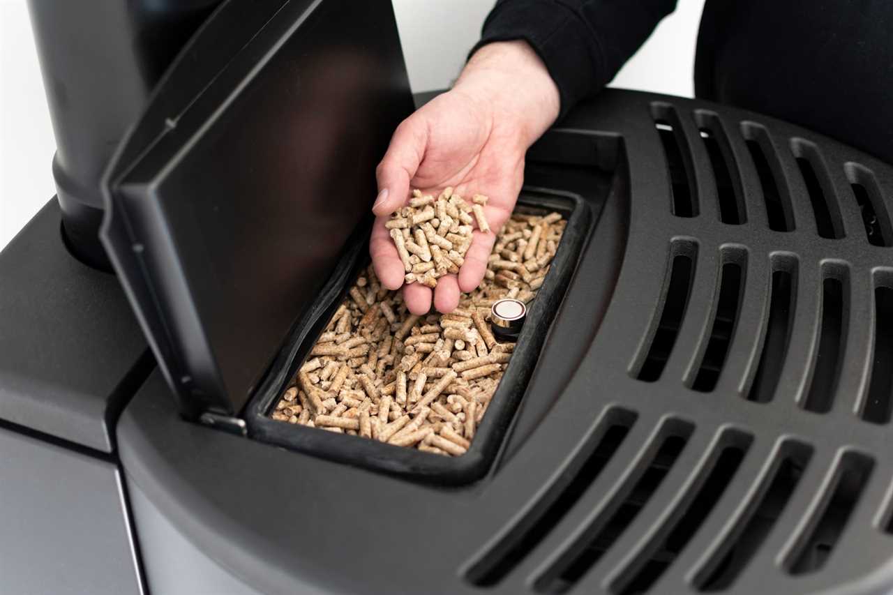 Pellet stove, man holding granules in his hand above a modern black stove