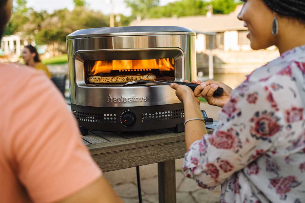 Woman taking out the pizza from Solo Stove Oven