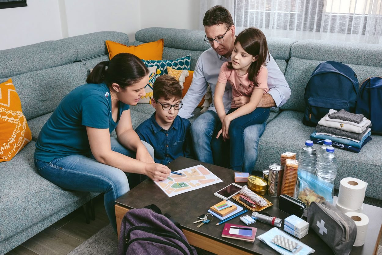 Mother Explaining To Her Family The Emergency Assembly Point while preparing and packing emergency backpacks and supplies