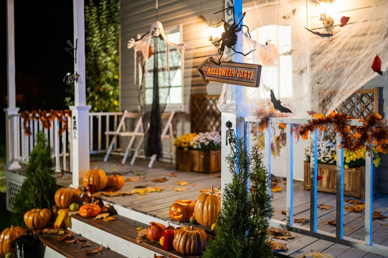 Halloween Jack O Lantern Pumpkins On A Porch with decorations for a Halloween party in the background