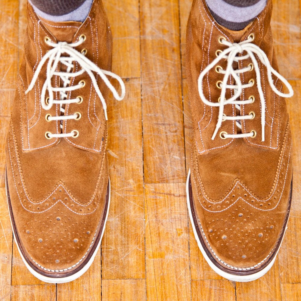 Close Up Of Mans Feet Wearing Suede Boots on wooden shoes