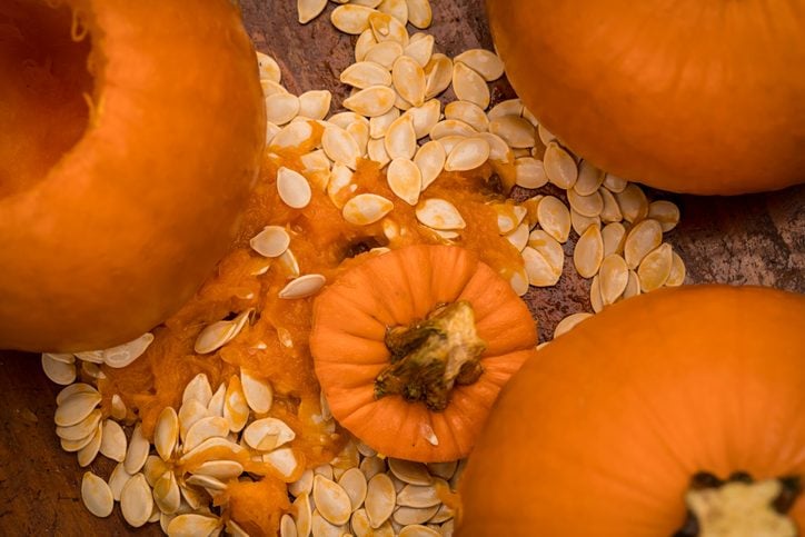 Cleaning out pumpkins with the innards scattered around pumpkins on a wooden surface in a residential home