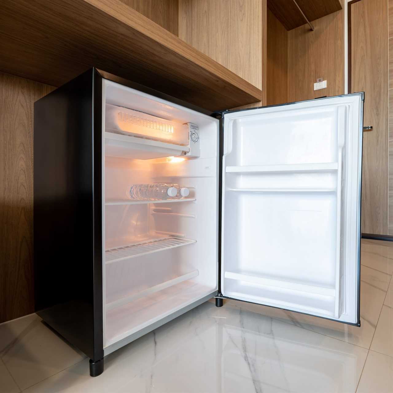 Opened small refrigerator under the wood counter and in front of enter door delux room at resort and hotel.