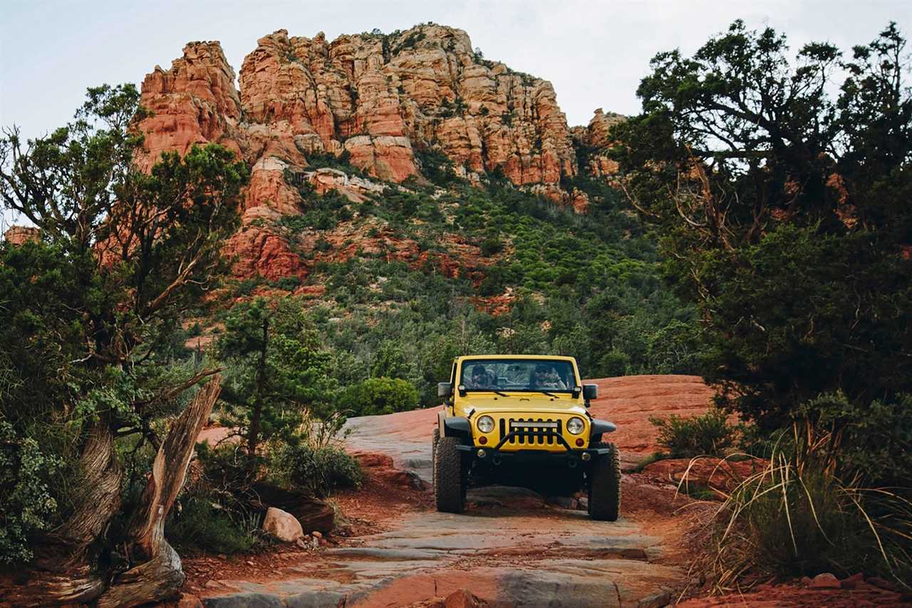 Yellow off-road vehicle moving on rocks at mountains against sky