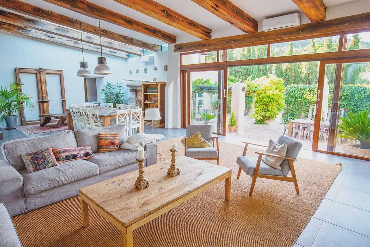 Elegant farmhouse living area with sofas and easy chairs and patio doors open on to garden